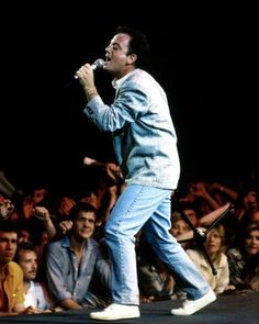 a man standing on top of a stage holding a microphone in front of a crowd