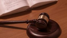 a wooden judge's gavel sitting on top of a table next to an open book