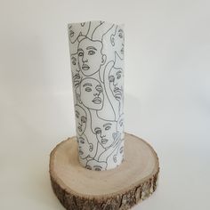 a white and black vase sitting on top of a tree stump