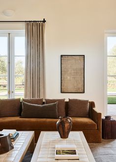 a living room with couches, tables and two vases on the coffee table