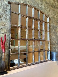 an old window frame with a broom on the mantle next to it and a brick wall in the background