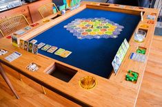 a wooden table topped with a board game on top of a hard wood floor next to a chair