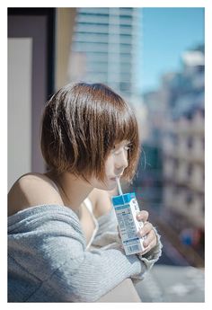 a woman holding a toothbrush in her hand and leaning against a window sill