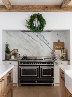 a stove top oven sitting inside of a kitchen next to a wooden countertop under a wreath