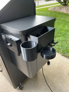 an outdoor grill with two cups on the burner and one cup in the bottom drawer