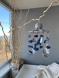 a blue and white wind chime hanging from a tree in a room next to a window