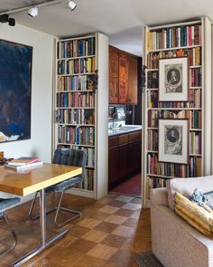 a living room filled with furniture and bookshelves next to a dining room table