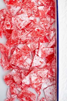 red and white pieces of glass sitting on top of a blue tray in the snow