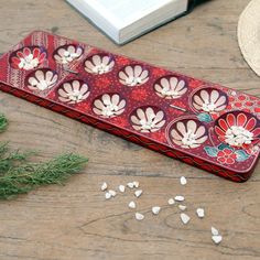 a red tray with white flowers on it next to an open book and some seaweed