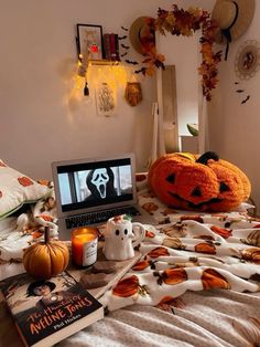 a laptop computer sitting on top of a bed covered in pumpkins and other decorations