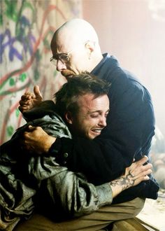 two men hugging each other in front of graffiti