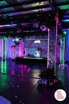 a stage set up for a party with purple and green lights on the sidelines