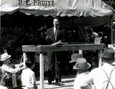 a man in a suit and tie standing at a podium with other people around him