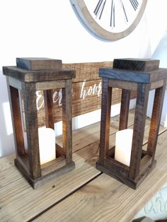 two wooden lanterns sitting on top of a wooden table next to a wall mounted clock