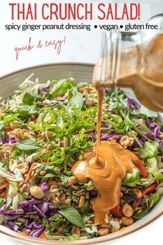 a bowl filled with salad and dressing being drizzled on top of it