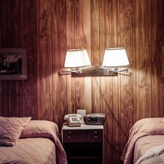 black and white photograph of two twin beds in a room with wood paneled walls