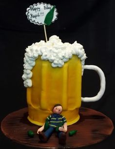 a cake made to look like a beer mug with a man sitting on the table