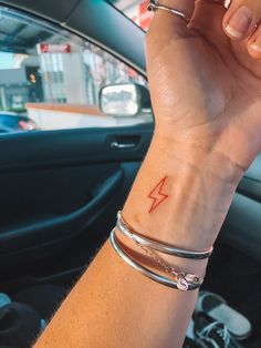 a woman's arm with a lightning tattoo on it, sitting in a car