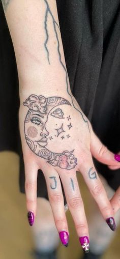 a woman's hand with tattoos on it and the moon in the sky above her