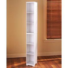 a tall white bookcase stands in front of a window