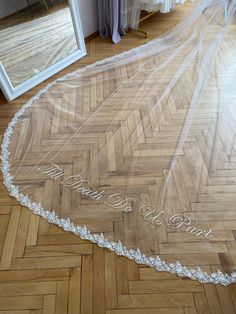 a bride's wedding veil is laying on the floor in front of a mirror