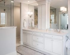 a large white bathroom with double sinks and mirrors on the wall, along with two walk in shower stalls