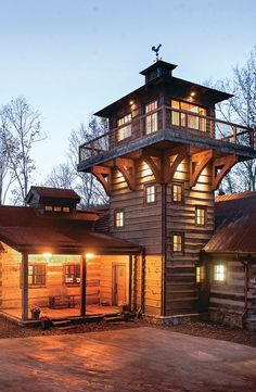 a large wooden building sitting next to a forest filled with lots of trees and lights