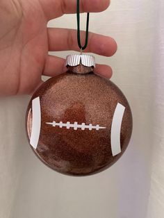 a hand holding a brown ornament with a football design on it's side