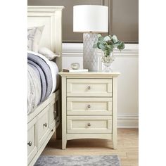 a white night stand with drawers and a lamp