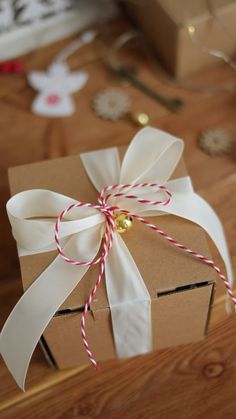 a brown box with a white ribbon tied around it on top of a wooden table