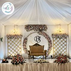 a couch sitting under a white tent with flowers on the table and chandelier