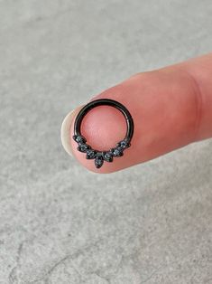 a finger with a small black ring on it