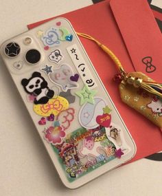 a cell phone with some stickers on it next to a notepad and envelope