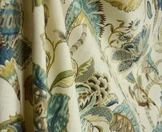 a close up view of a curtain with flowers and leaves in blue, green, yellow and white colors