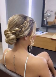 a woman sitting in front of a mirror with her back turned to the camera and wearing a bra