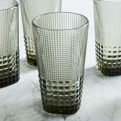 four clear glass cups sitting on top of a marble counter