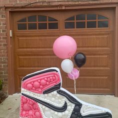 a pair of sneakers with balloons attached to them in front of a garage door,