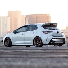 a white car parked in front of a city skyline