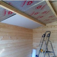 a ladder is in the corner of a room with wood paneling on the walls