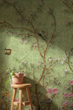 a bird is sitting on a tree branch next to a potted plant and wallpaper