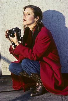 a woman sitting on the ground holding a camera