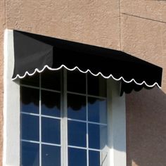 an awning on the side of a building with windows in front of it and a clock