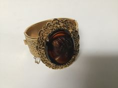 "Free shipping to the USA and Canada. A remarkable Victorian style cameo cuff bracelet.  Simply exquisite with stunning details on this beautiful bracelet.  The clasp is a hinged slide in perfect working condition and has a safety chain.  The cameo is an early celluloid and a wonderful piece of vintage jewelry. Measurements: 7\" circumference  1\" band width Cameo: 1 5/8\" 1 1/4\"" Antique Oval Bangle For Formal Occasions, Antique Hinged Bracelet For Formal Occasions, Antique Hinged Bracelets For Formal Occasions, Elegant Oval Cabochon Cuff Bracelet, Formal Intaglio Bangle Jewelry, Vintage Hinged Bangle For Formal Occasions, Antique Cuff Bracelet For Formal Occasions, Elegant Cabochon Cuff Bracelet For Formal Occasions, Formal Oval Costume Jewelry Bracelets