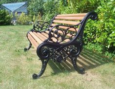 a wooden bench sitting in the middle of a lush green field next to bushes and trees