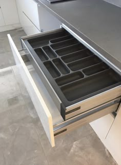 an open drawer in the middle of a kitchen with drawers on both sides and doors down