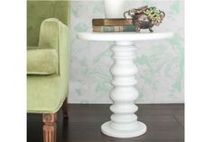 a white table topped with books next to a green chair