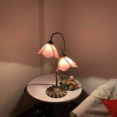 a lamp that is sitting on top of a table next to a flower pot and pillow