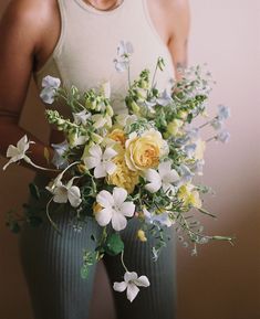 a woman holding a bouquet of flowers in front of her face and wearing tights