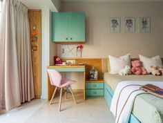 a bedroom with a bed, desk and chair in it next to a window that has drapes on the windowsill