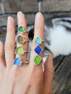 a woman's hand with five different colored rings on it